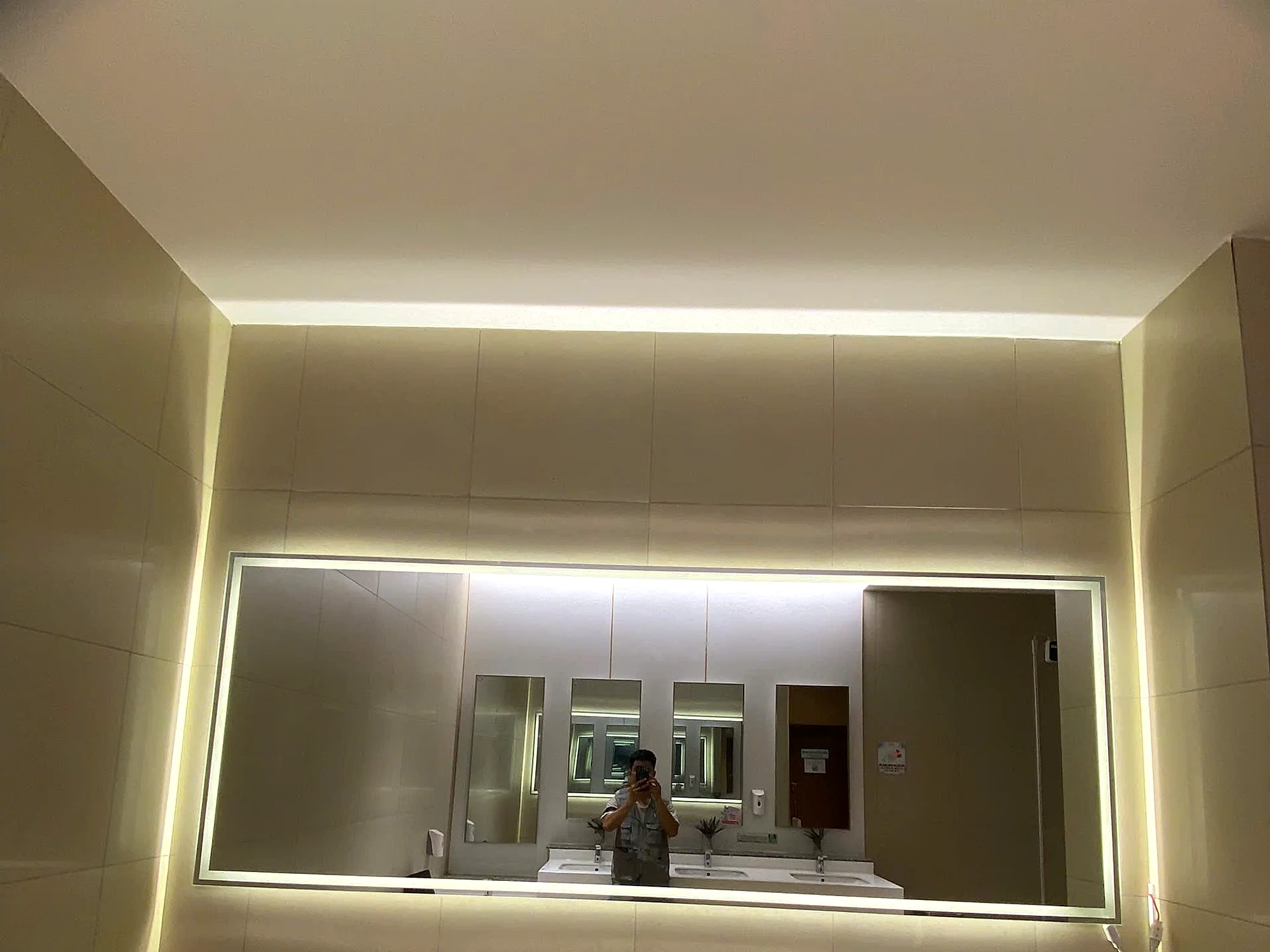 Nhiều gương LED cùng kích thước lắp đồng bộ tại các khu vệ sinh PARC MALL, phản chiếu dãy gương giống nhau trên tường ốp đá, thể hiện độ đồng đều về khe hở và cao độ khi thi công gương hàng loạt
