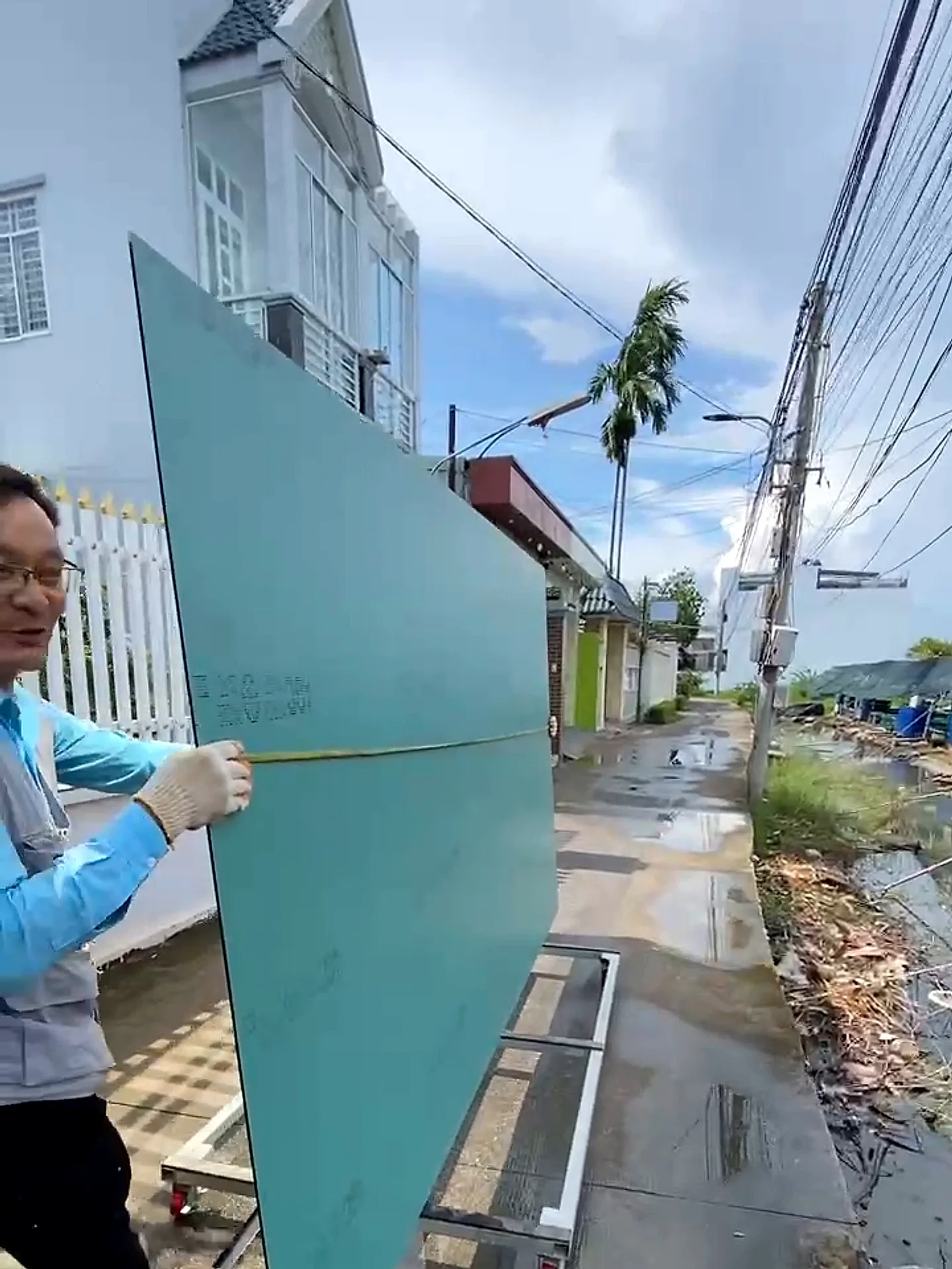 Thợ khiêng tấm gương soi khổ lớn còn nguyên lớp film bảo vệ dọc theo lối đi vào nhà, khâu vận chuyển an toàn tránh nứt vỡ cạnh gương khi lắp đặt tận nơi