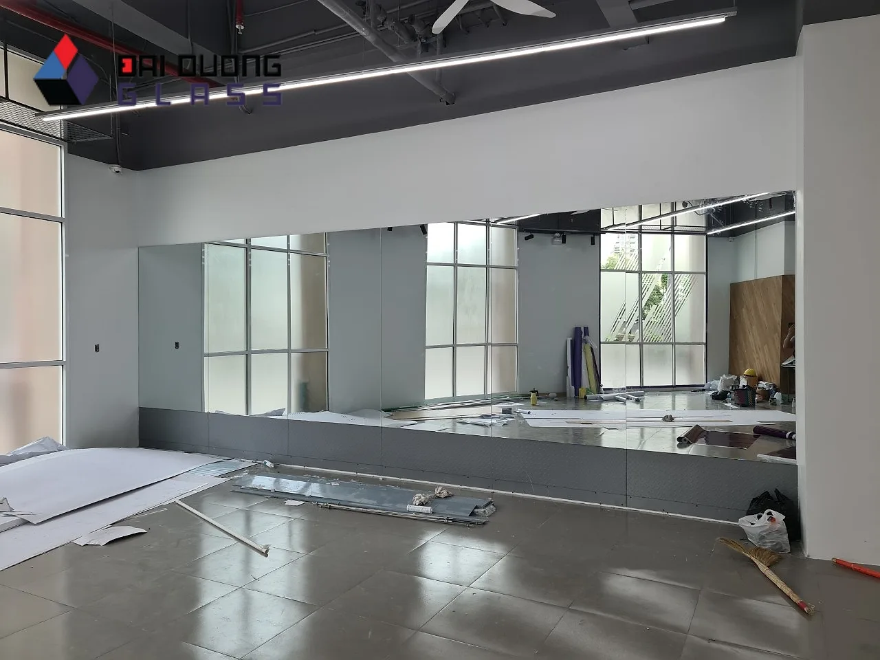 Cắt Gương Cần Thơ: Đặt Gương Công Trình Theo Lô Từ Xưởng 2 Phòng gym có vách gương khổ lớn chạy dọc tường, logo Đại Dương Glass ở góc ảnh