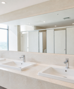 gương nhà vệ sinh khách sạn với gương dài liên tục trên ba chậu rửa trắng եւ quầy đá sáng