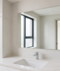 Gương phòng tắm chữ nhật phía trên lavabo trắng, gạch xám sáng và ánh sáng tự nhiên