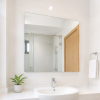 gương phòng tắm hình chữ nhật phía trên lavabo trắng trong căn hộ sáng sạch với gạch sáng màu