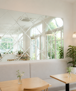 gương quán cafe trong không gian sáng với gương tường, bàn gỗ, cây xanh và cửa sổ lớn