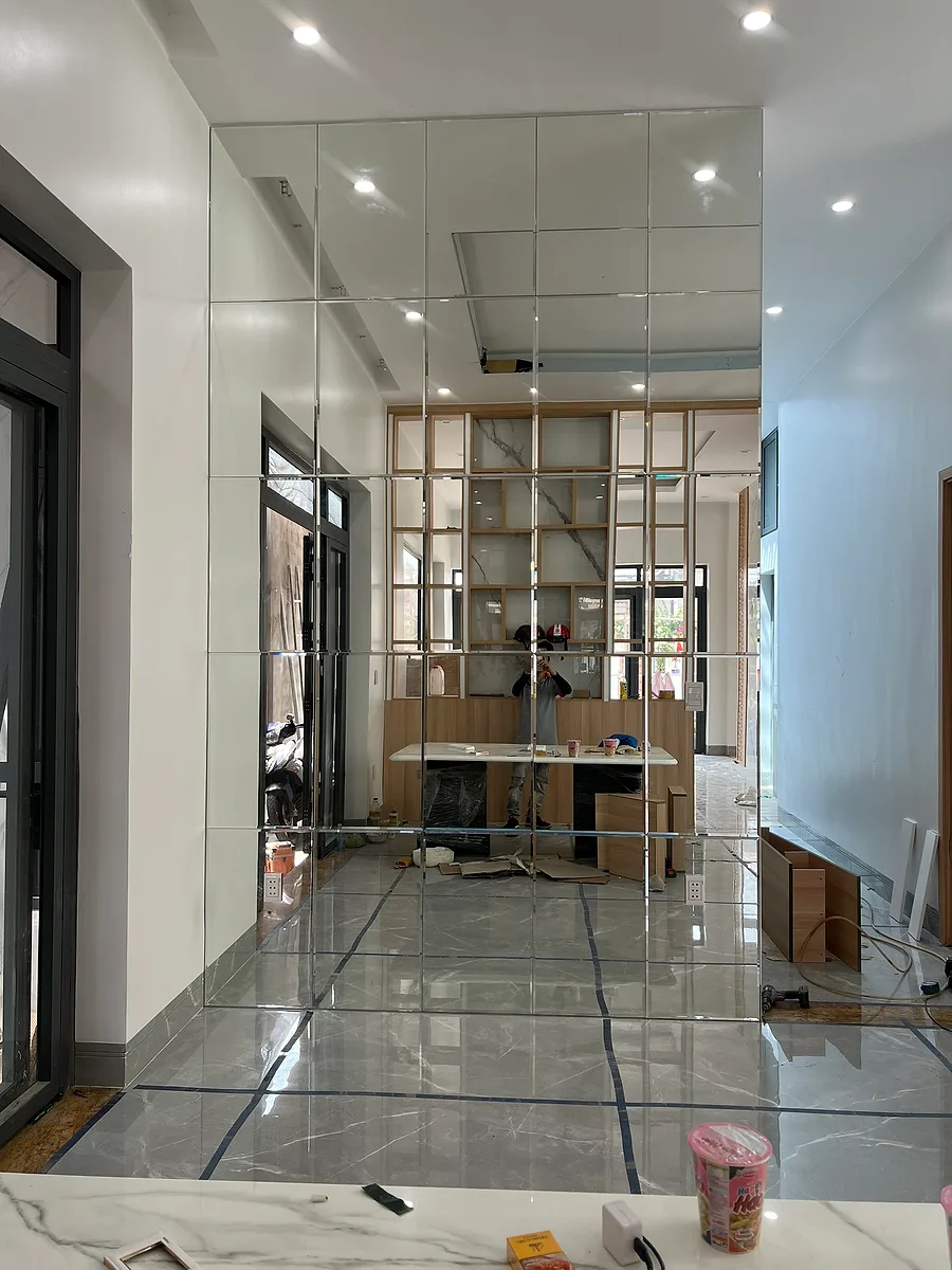 Xưởng Gương Bình Dương: Gương Cho Nhà Xưởng, Căn Hộ, Khách Sạn 3 Hai thợ căn chỉnh tấm gương dán tường khổ lớn trong nhà mới hoàn thiện