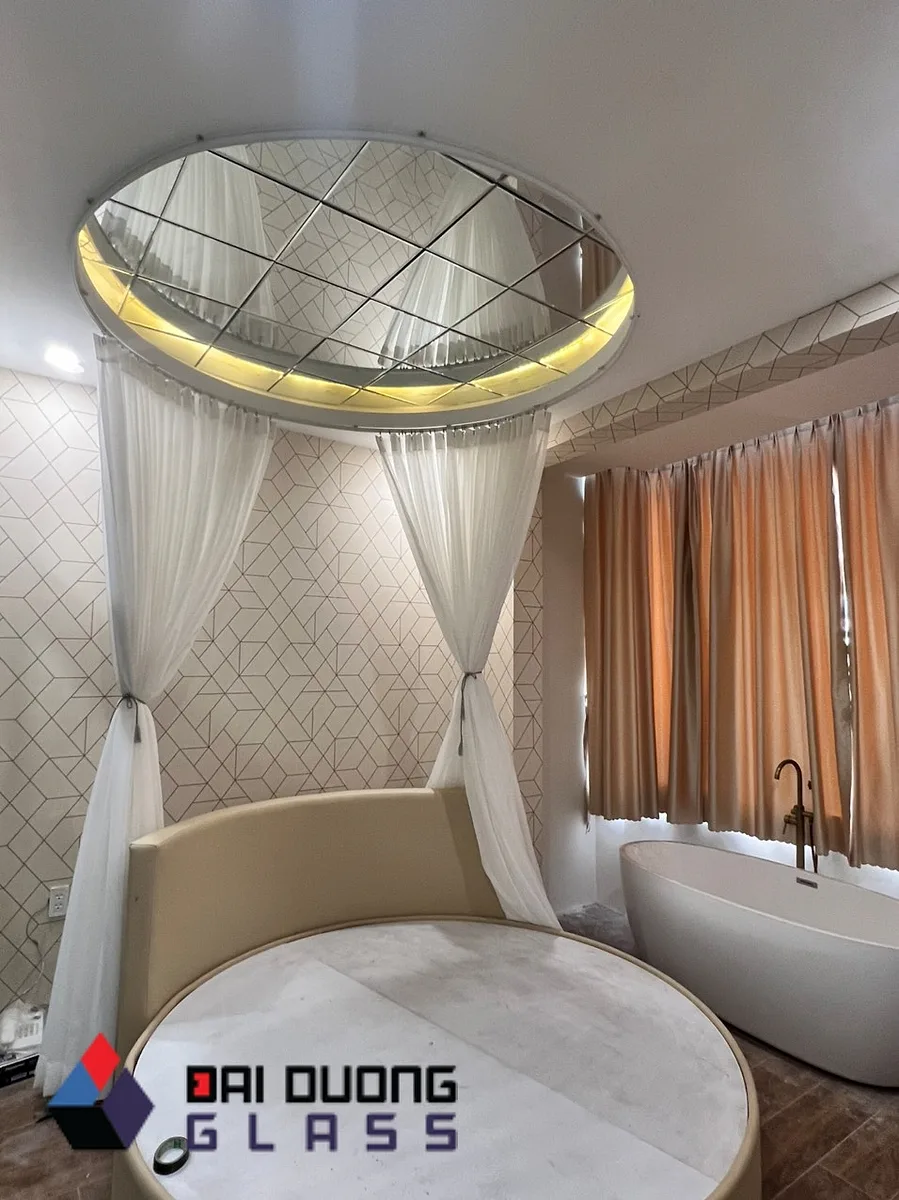 Phòng khách sạn có trần gương tròn và bồn tắm đặt cạnh giường