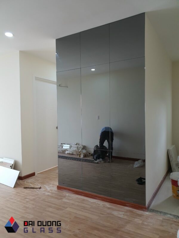 Tấm gương xám khói cao từ sàn đến trần đang được thợ Đại Dương Glass lắp